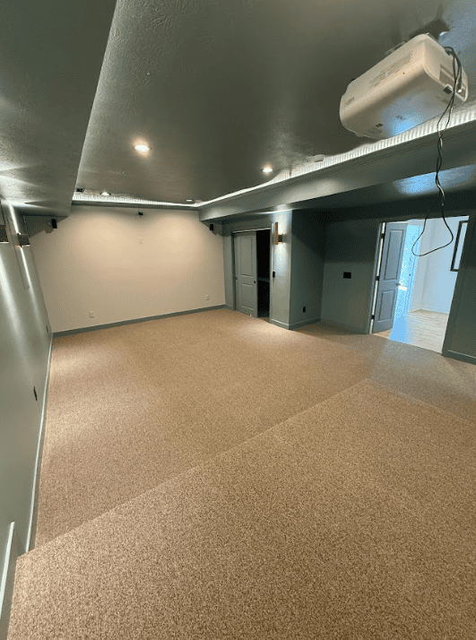 Finished basement family room with custom built-in shelving and recessed lighting