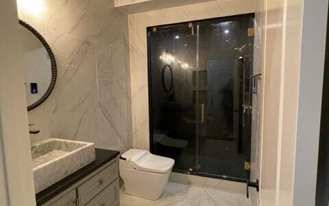 Marble tiled bathroom renovation with glass shower enclosure